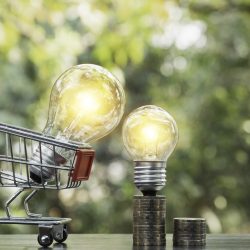 Energy saving light bulb with stacks of coins and shopping cart Energy saving light bulb with stacks of coins and shopping cart for saving, financial and shopping concept and copy space for insert text.