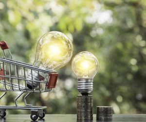 Energy saving light bulb with stacks of coins and shopping cart for saving, financial and shopping concept  and copy space for insert text.